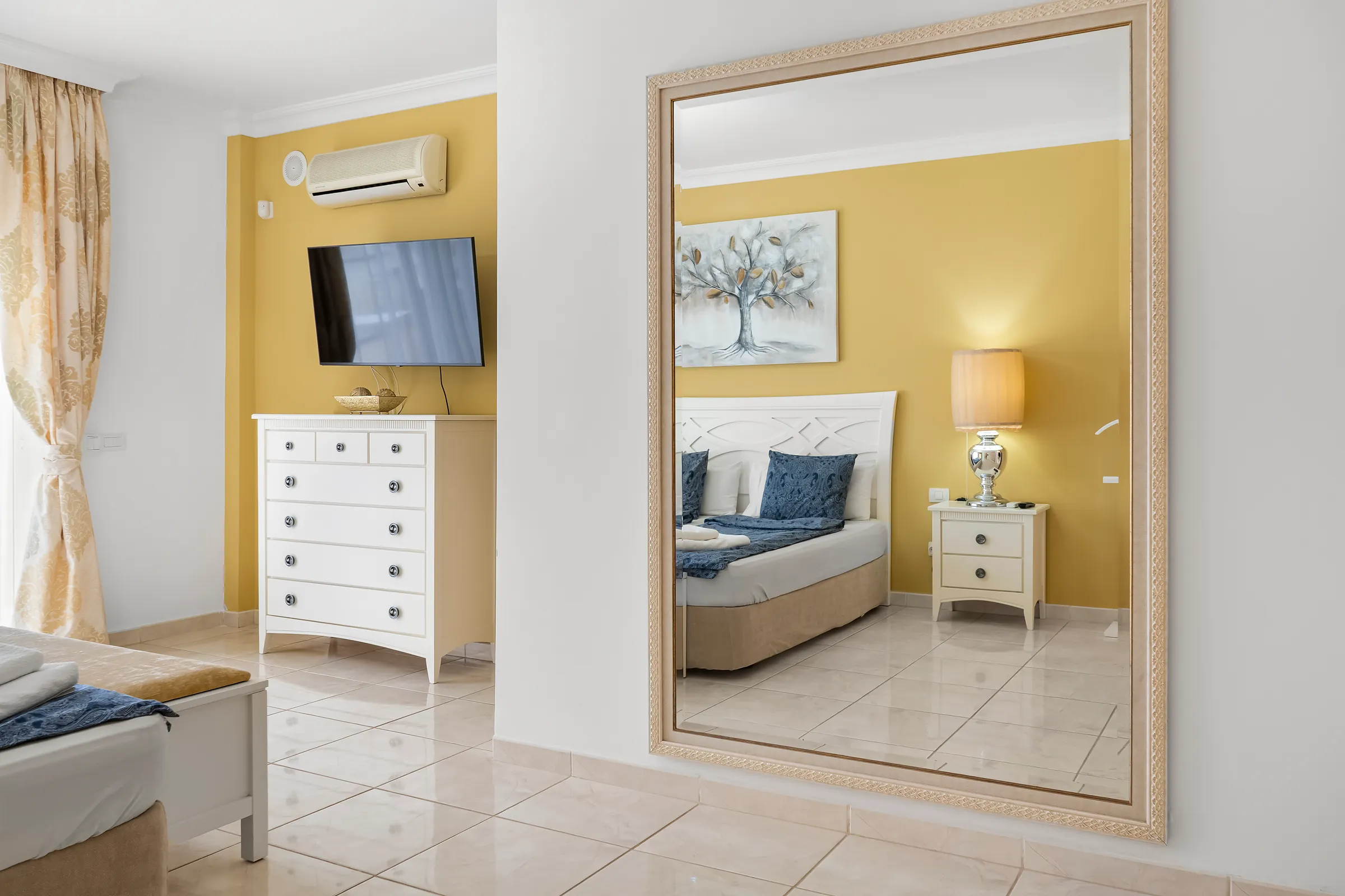 Schlafzimmer 1 der Villa Alexander mit großem Spiegel, Kommode und Fernseher