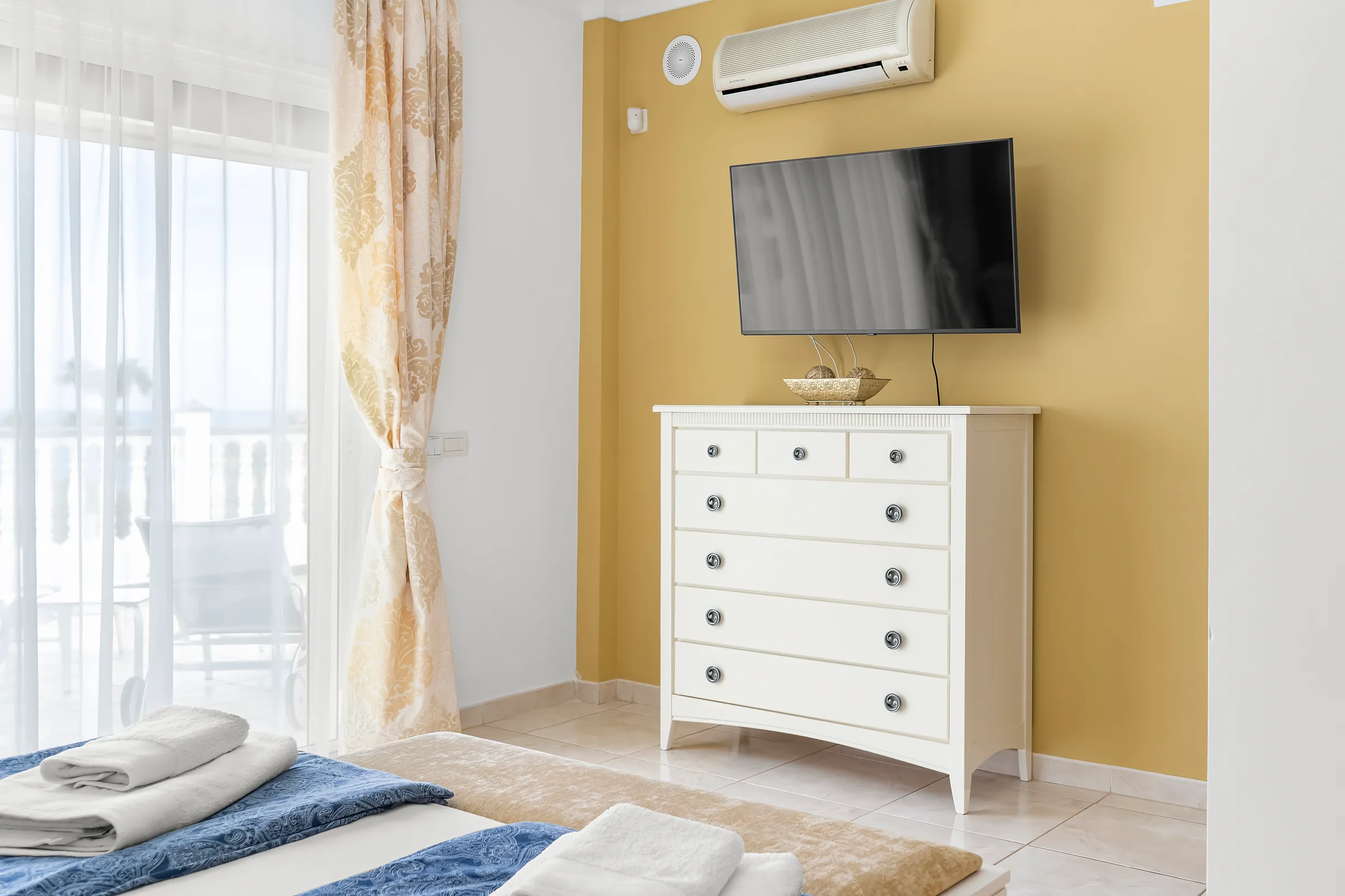 Schlafzimmer 1 der Villa Alexander mit Fernseher, Kommode und Zugang zur Terrasse
