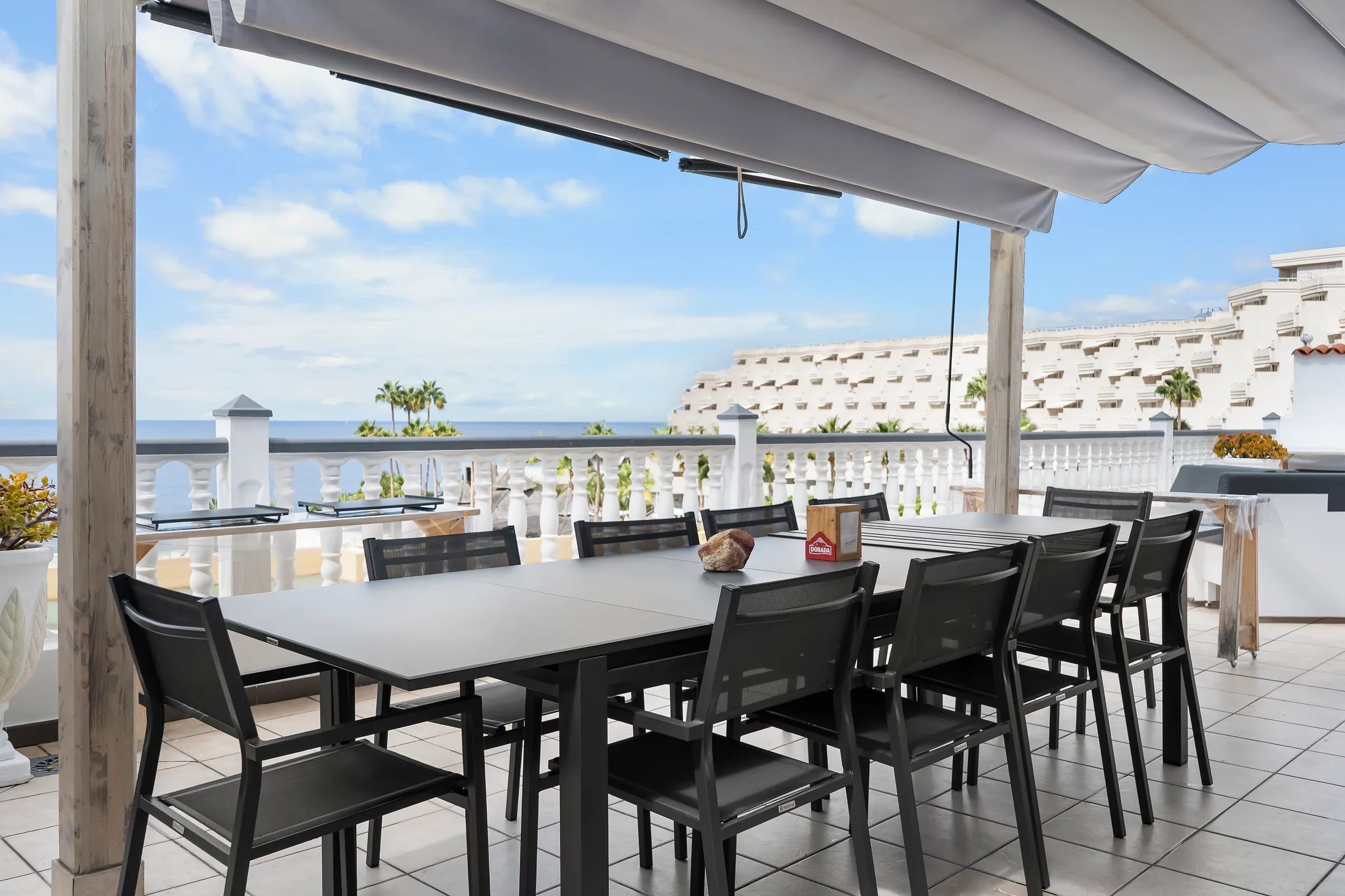 Überdachte Terrasse der Villa Alexander mit großem Esstisch und Meerblick