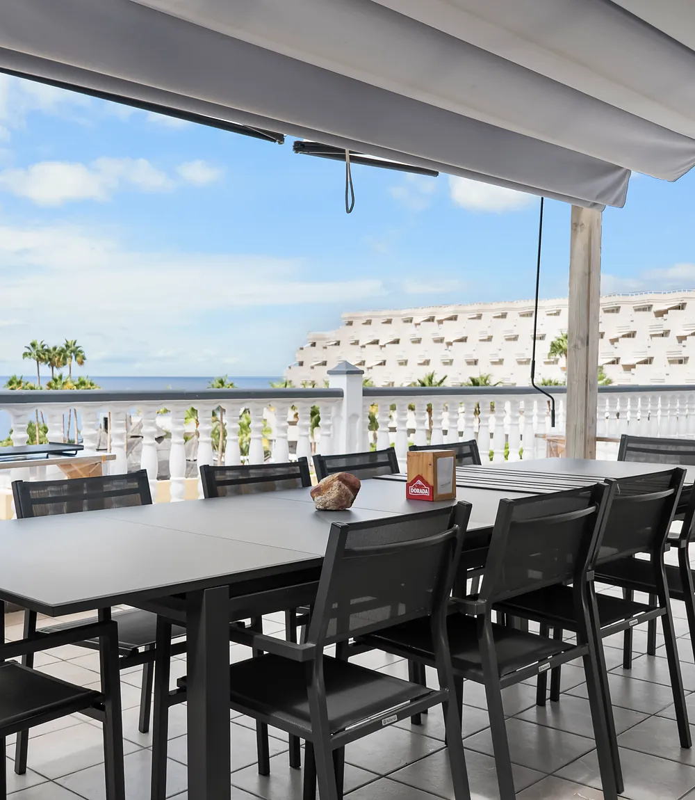 Überdachte Terrasse der Villa Alexander mit großem Esstisch und Meerblick